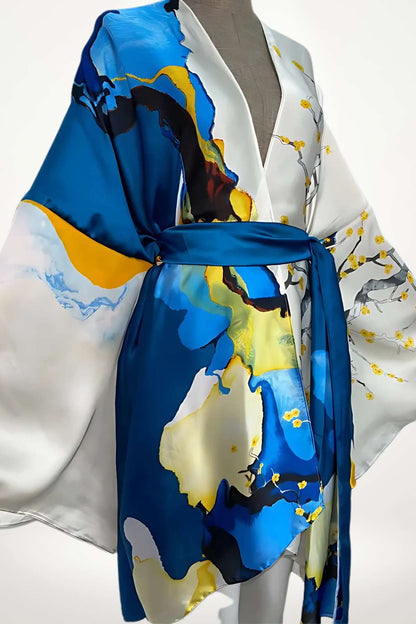 Kimono en satin blanc avec motifs bleus et jaunes, ceinturé, drapé élégamment sur un mannequin
