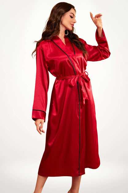 Kimono satin rouge brillant avec des détails noirs, porté par une femme en posture élégante, sur fond neutre. Kimono femme, style japonais.