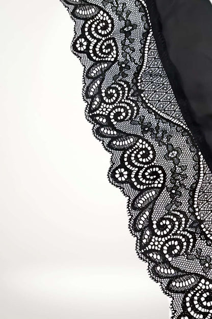 Détail d'un tissu en dentelle noire avec des motifs floraux et des courbes élégantes sur fond clair