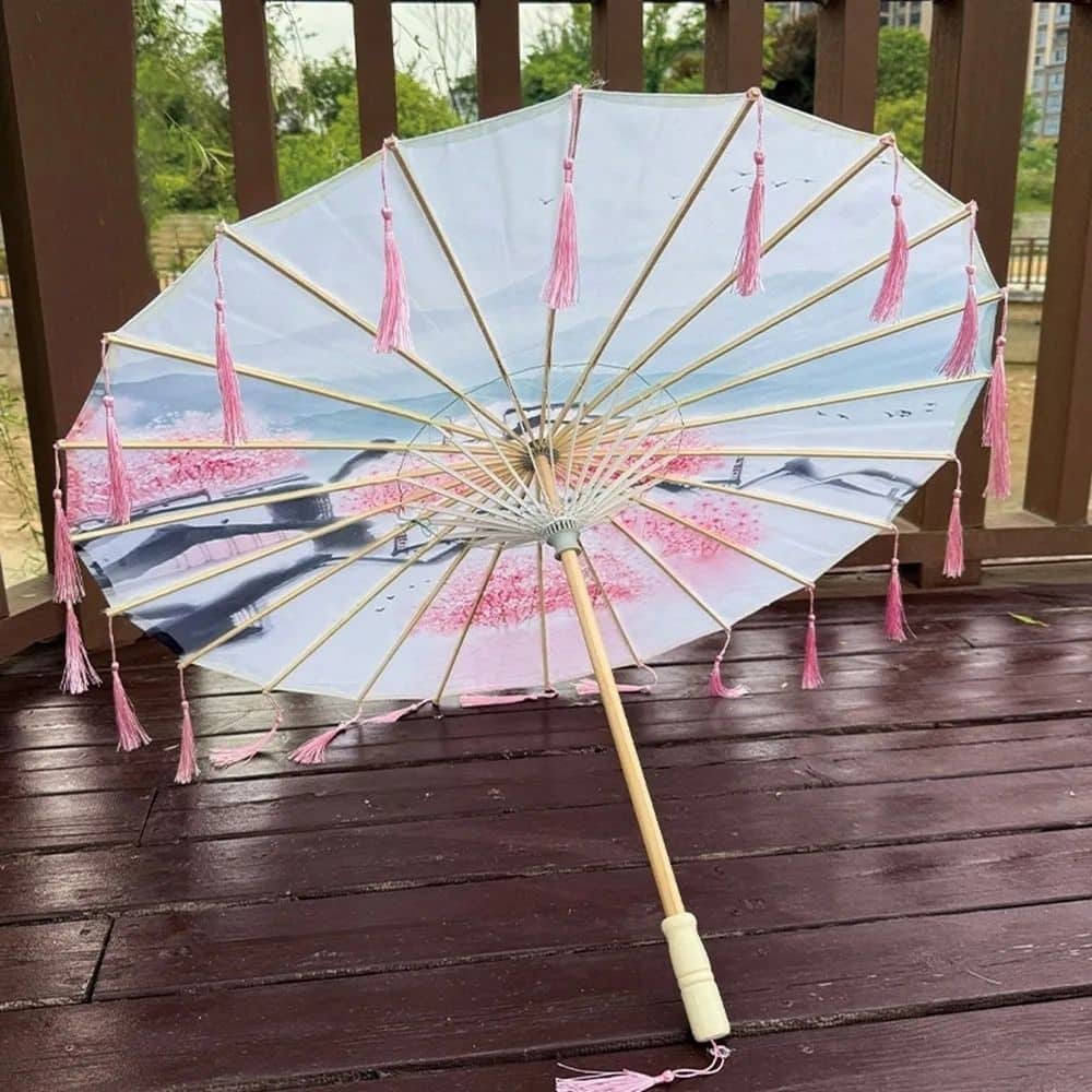 Ombrelle adulte anti-UV rose avec des franges, motifs floraux et structure en bois sur un fond en bois foncé