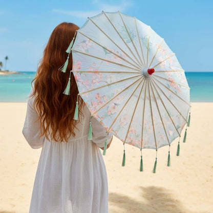 Femme aux cheveux longs portant une ombrelle bleue ornée de fleurs, sur une plage ensoleillée