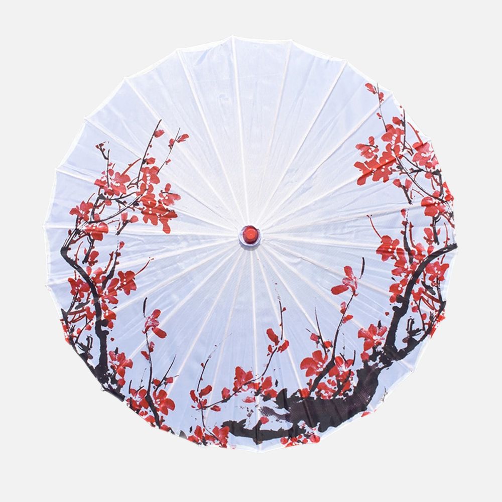 Ombrelle blanche ornée de motifs floraux rouges sur un fond clair, avec une structure en papier délicat