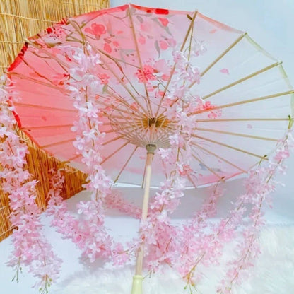 Ombrelle fleurie rose avec des motifs floraux, décorée de guirlandes de fleurs délicates en tissu