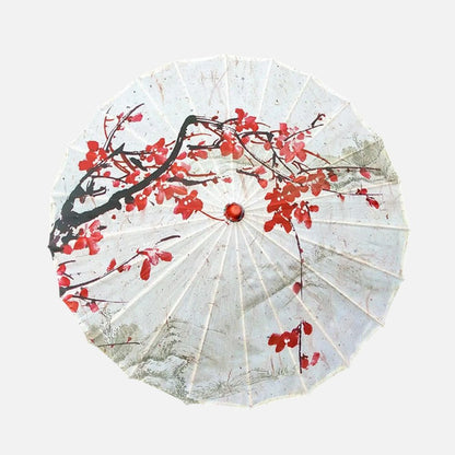 Ombrelle japonaise blanche ornée de motifs floraux rouges et noirs, posée sur un fond neutre