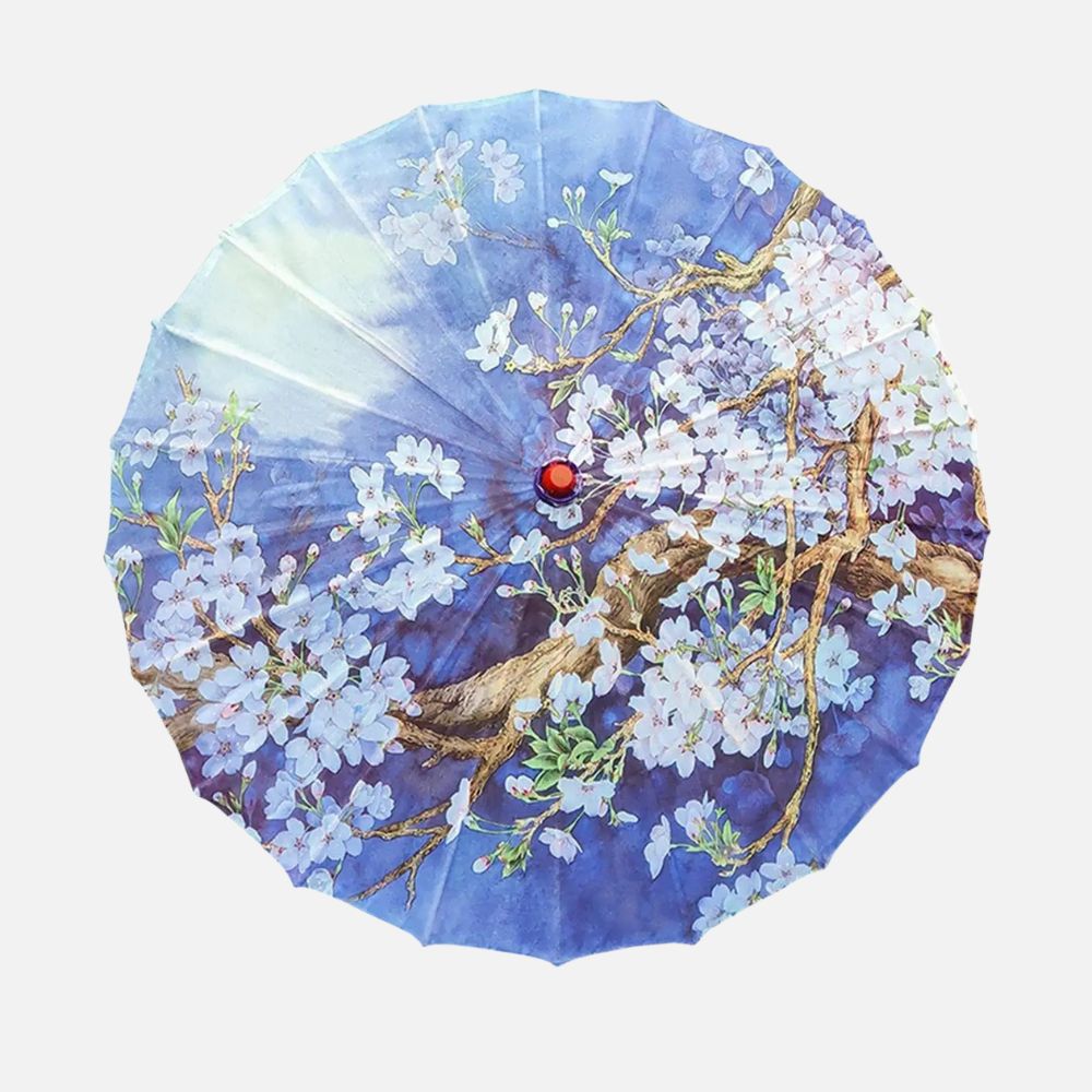 Ombrelle japonaise en tissu bleu décorée de fleurs blanches et de branches, avec un bouton rouge au centre