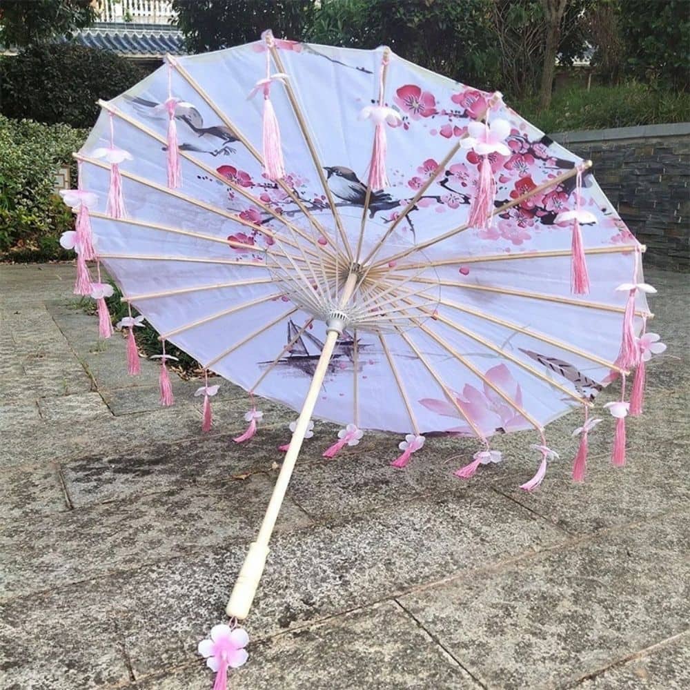 Ombrelle anti-UV rose ornée de fleurs, avec des franges et un motif délicat sur un fond blanc