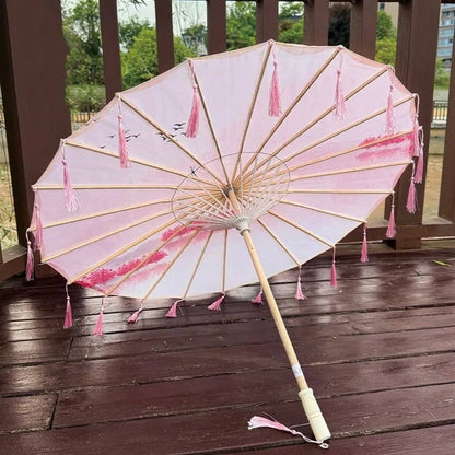 Ombrelle pour femme de couleur rose avec des franges, motif floral et structure en bois sur un fond en bois