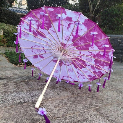 Ombrelle anti-UV rose avec des motifs floraux, ornée de franges violettes et d'une tige en bois