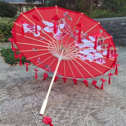Ombrelle universelle anti UV rouge ornée de motifs floraux, posée sur un sol en pierre grise