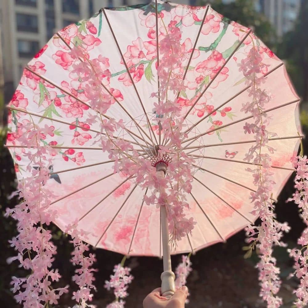 Parapluie japonais traditionnel rose orné de fleurs, avec une structure en bois et un décor floral délicat
