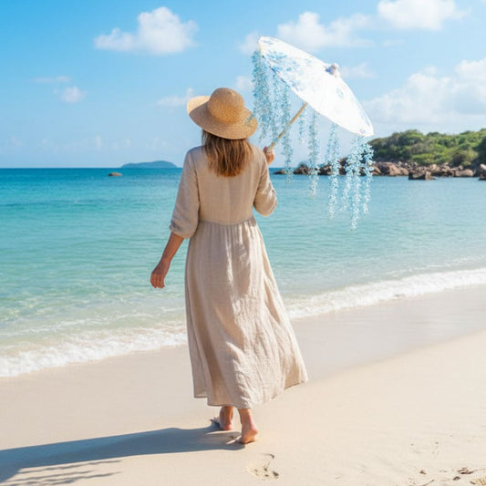Femme marchant sur la plage, portant une robe beige et un parapluie japonais bleu ciel, avec mer et ciel en