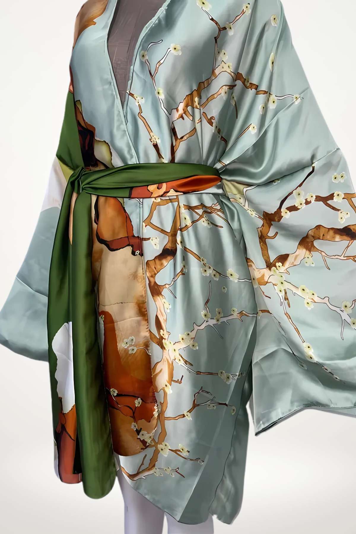 Robe kimono en satin bleu avec motifs floraux et ceinture verte, drapée élégamment sur un mannequin