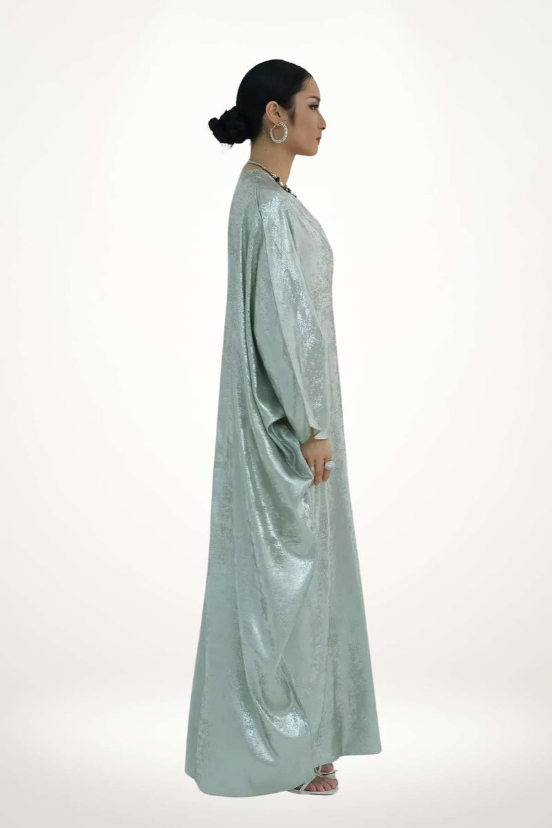 Abaya kimono en satin texturé vert à l’éclat discret. Coupe fluide, design minimaliste et raffiné, idéale pour sublimer vos instants du quotidien ou vos occasions.