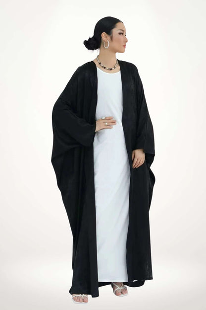 Abaya kimono satin moderne en velours texturé noir. Coupe fluide, design sobre et puissant pour une allure élégante au quotidien.