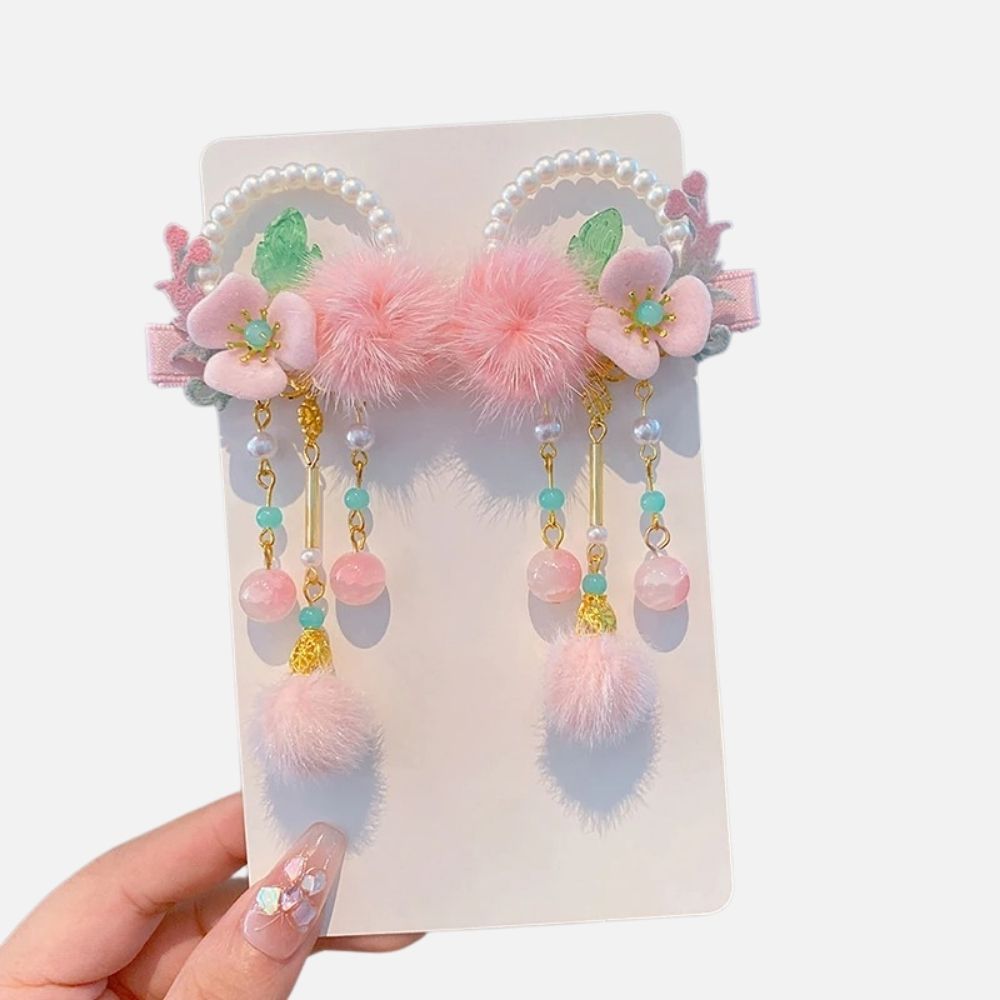 Un accessoire aux tons roses avec des fleurs, des pompons en fourrure et des perles colorées suspendues