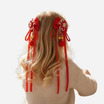 Une jeune fille aux cheveux blonds porte des nœuds rouges ornés de perles et de pompons