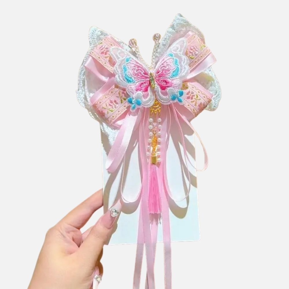 Un accessoire en satin rose avec un motif de papillon, orné de perles et de rubans délicats