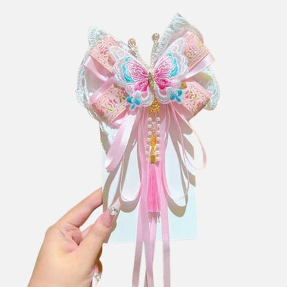 Un accessoire en satin rose avec un motif de papillon, orné de perles et de rubans délicats