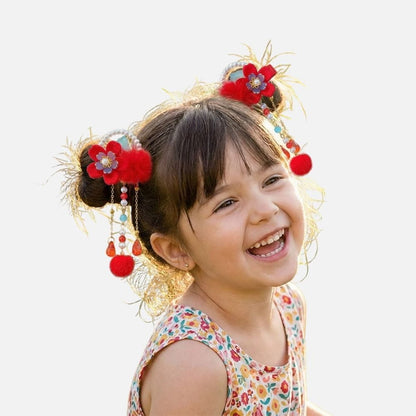 Une petite fille souriante porte une robe à motifs colorés et des accessoires de cheveux rouges et brillants