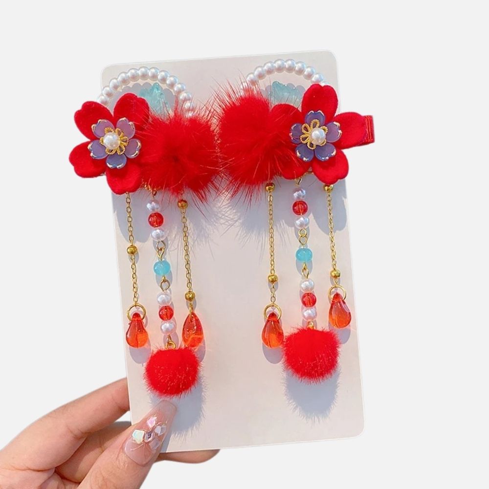 Accessoire de cheveux coloré avec des fleurs rouges, des pompons et des perles brillantes sur fond blanc