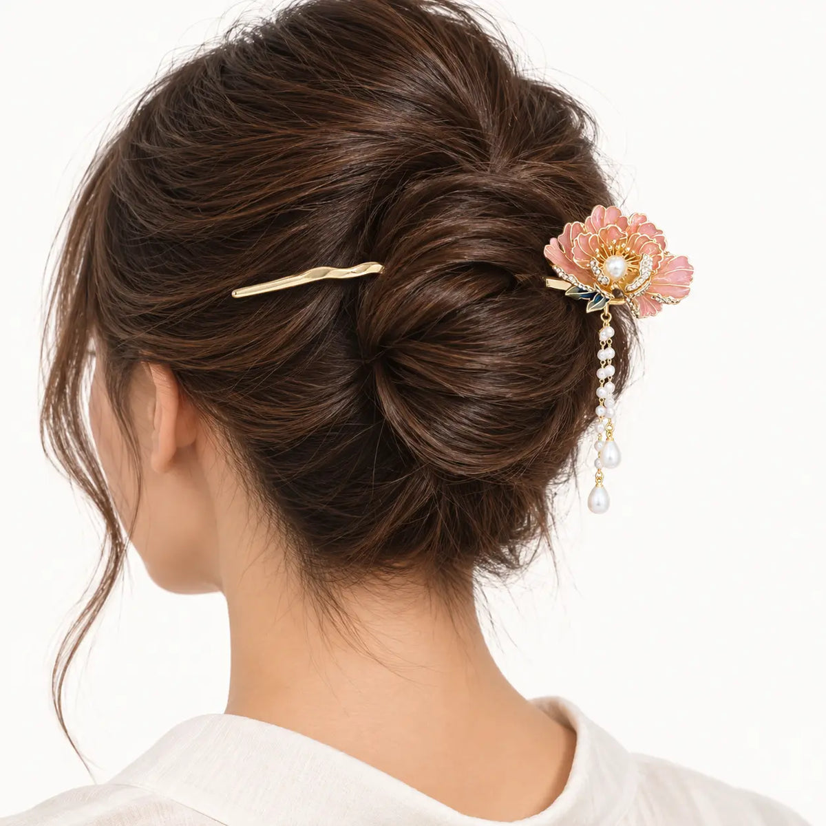 Chignon décoré d’un bijou doré à fleur et perles pendantes.