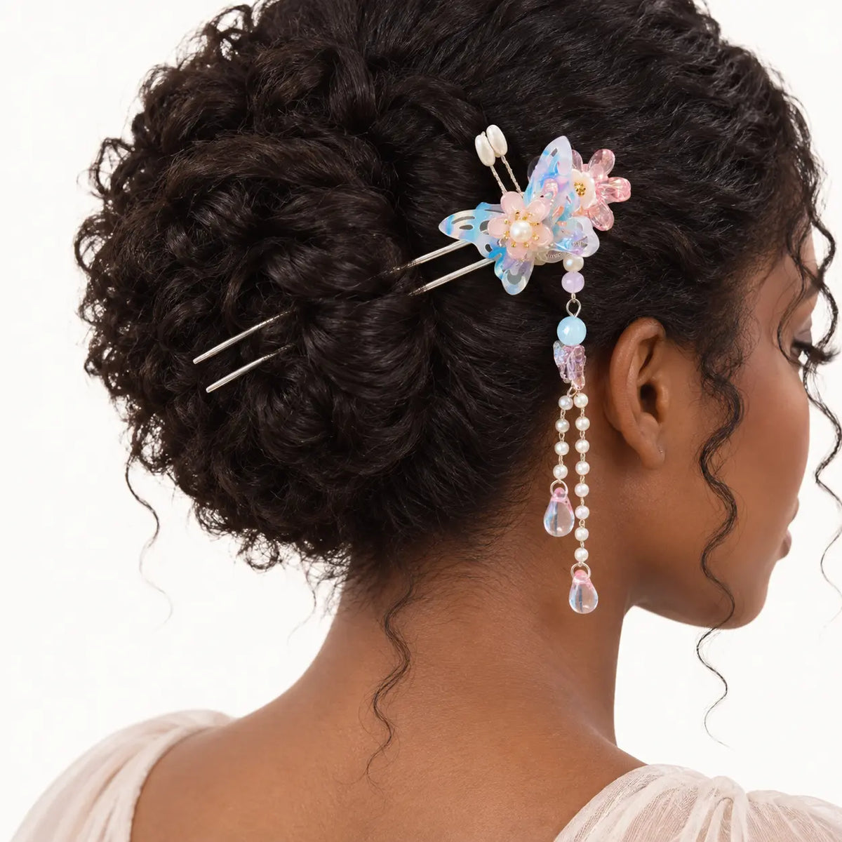 Chignon agrémenté d’un bijou à papillon bleu et pendants roses.