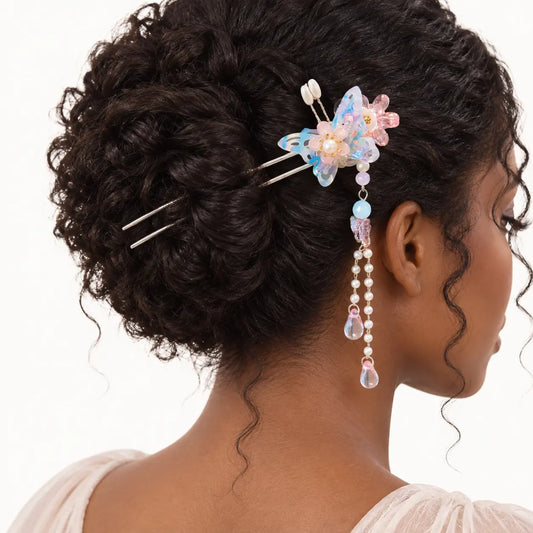 Chignon agrémenté d’un bijou à papillon bleu et pendants roses.