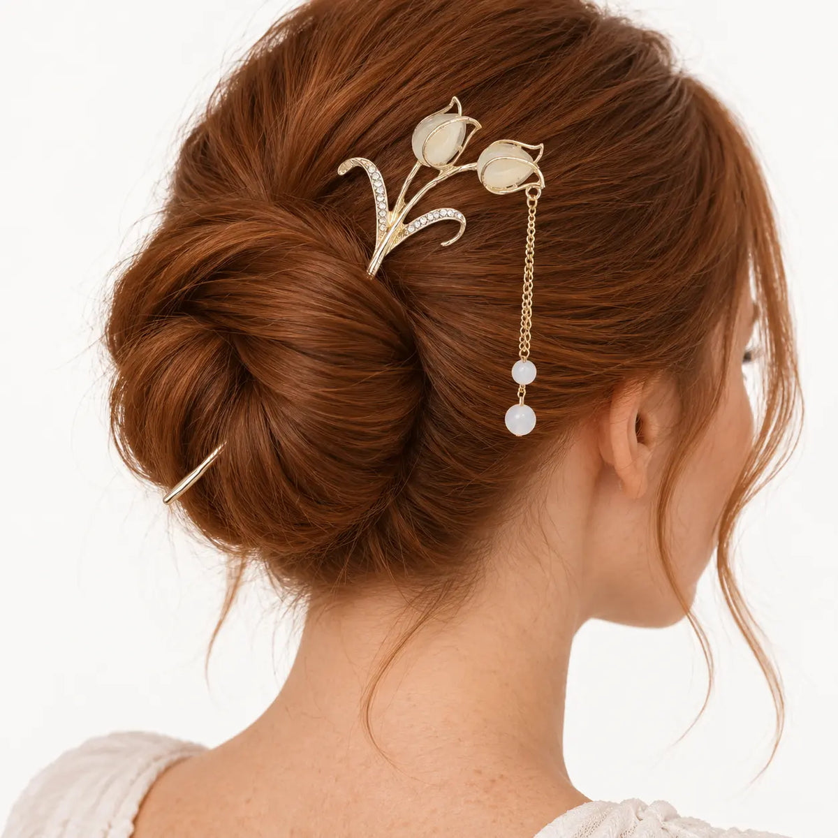 Chignon décoré d’un bijou à tulipes ivoire et chaîne dorée.