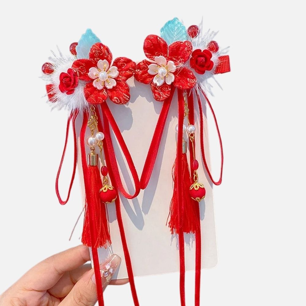 Un accessoire de cheveux rouge orné de fleurs, perles et rubans, sur un fond neutre