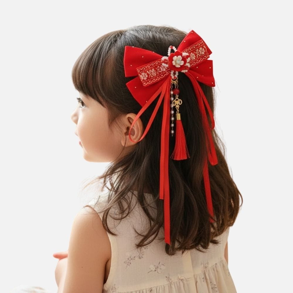Fille avec un nœud rouge orné de perles et de rubans, portant une robe claire avec des motifs floraux