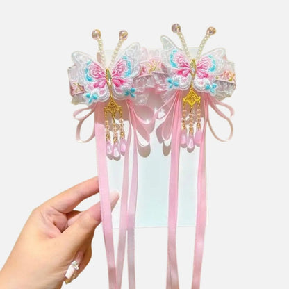 Un accessoire en satin rose avec des papillons brodés, perles et rubans, sur fond blanc
