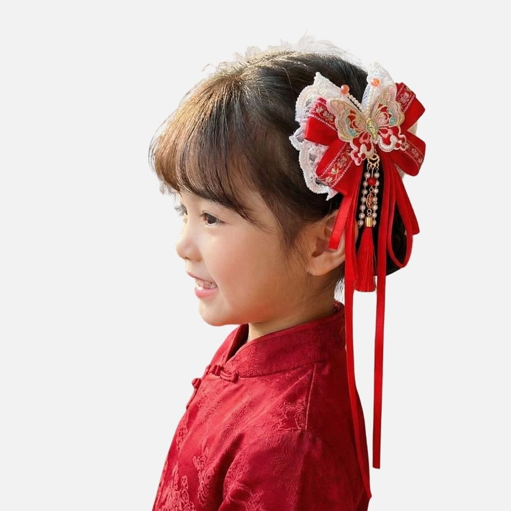 Fille souriante portant un kimono rouge avec un accessoire à cheveux en dentelle et rubans rouges