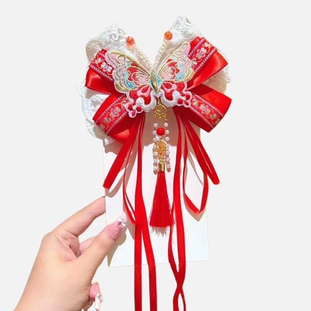 Un accessoire en satin rouge avec un motif de papillon, des perles et des rubans décoratifs