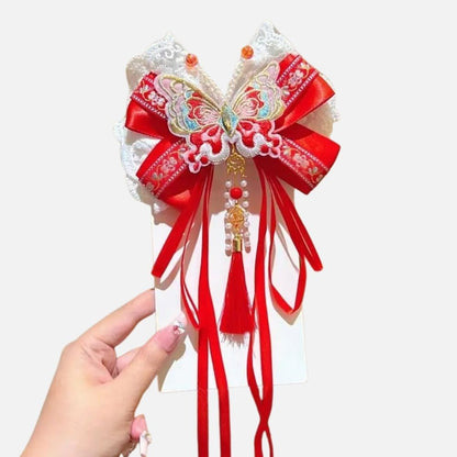 Un accessoire en satin rouge avec un motif de papillon, des perles et des rubans décoratifs