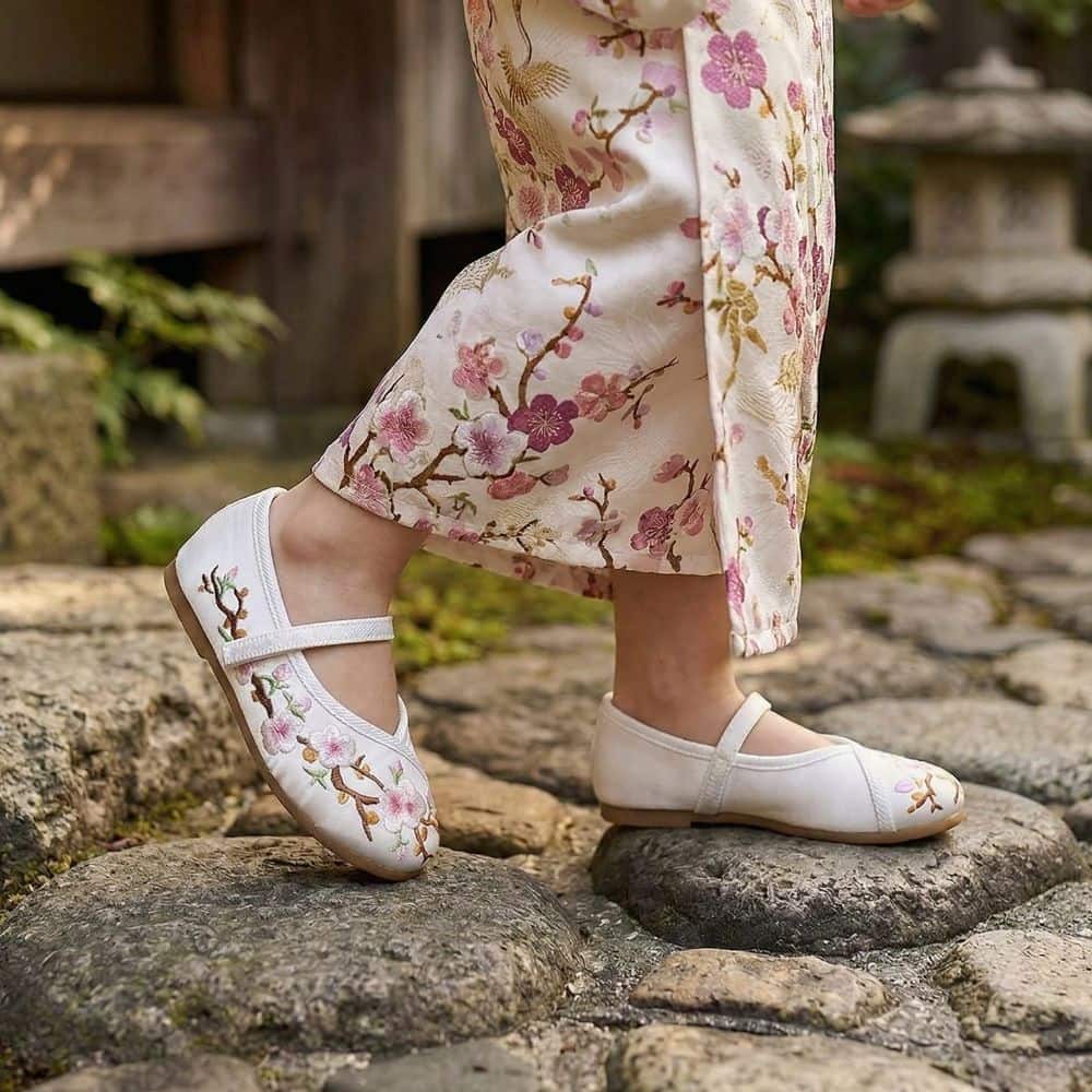 Une jeune fille porte des ballerines blanches sur des pierres, vêtue d'un kimono aux motifs floraux délicats