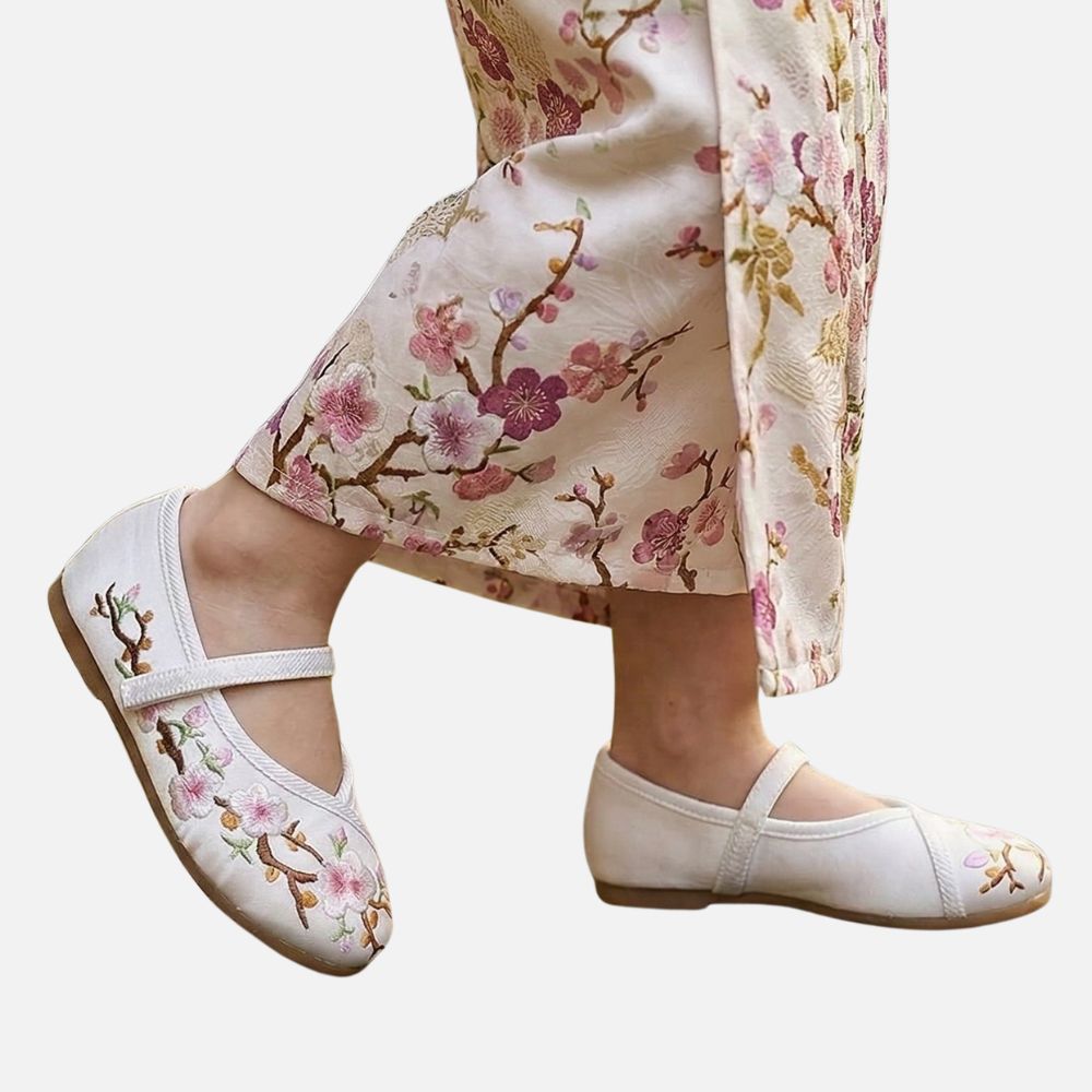 Une ballerine blanche ornée de fleurs brodées, portée avec une robe à motifs floraux pastel