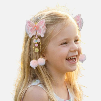 Fille souriante avec des cheveux blonds et un accessoire coloré en forme de papillon, décoré de pompons et perles