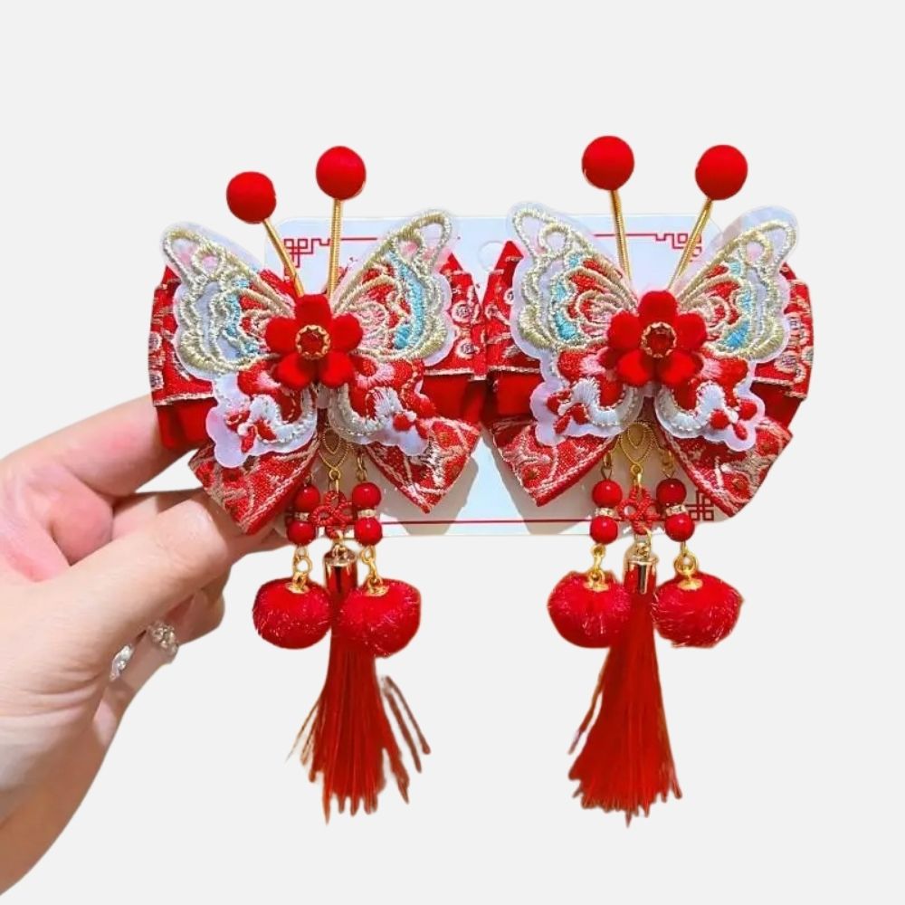 Deux accessoires en satin rouge ornés de motifs de papillons et de fleurs, avec des pompons et des franges