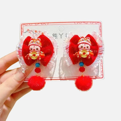 Deux accessoires en velours rouge ornés de pompons et de figurines, sur un fond blanc et décor floral