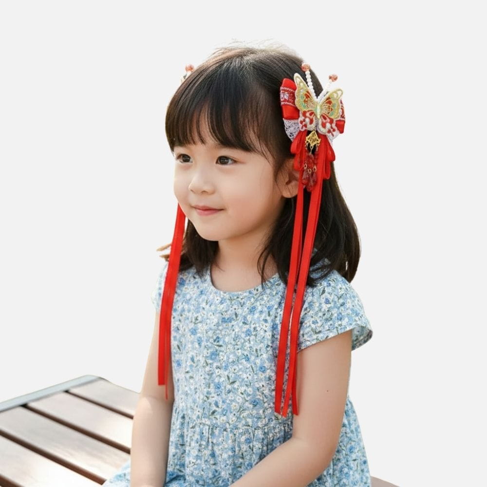 Fille souriante portant une robe bleue à fleurs et un accessoire rouge en forme de papillon dans les cheveux