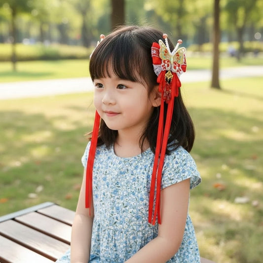 Fille souriante avec une robe à fleurs bleues et un accessoire rouge en forme de papillon dans un parc