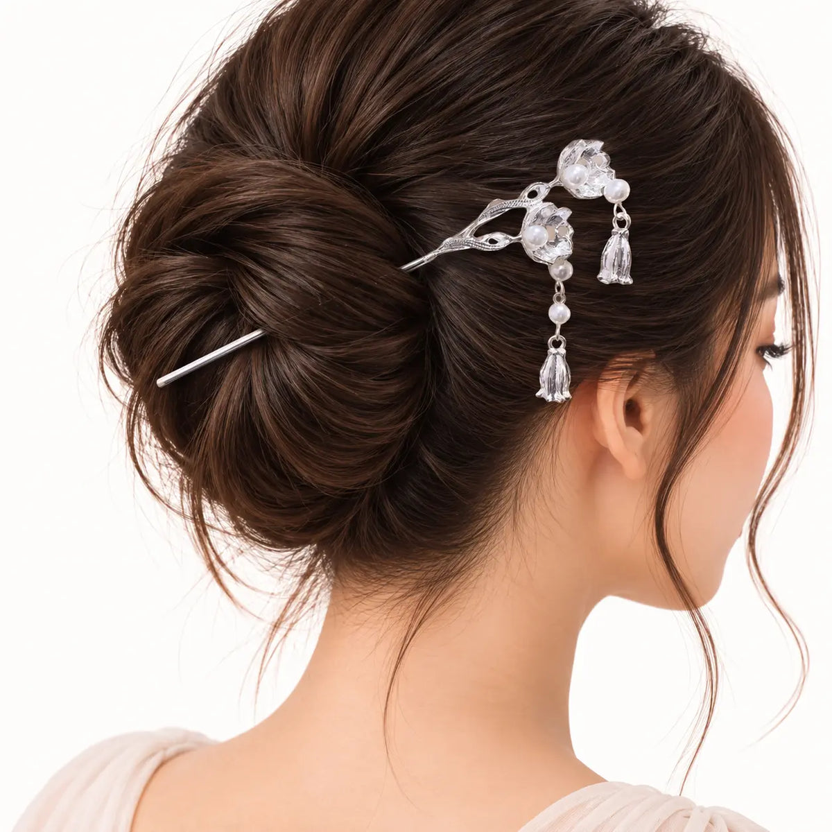 Chignon orné d’un bijou argenté à fleurs et perles.