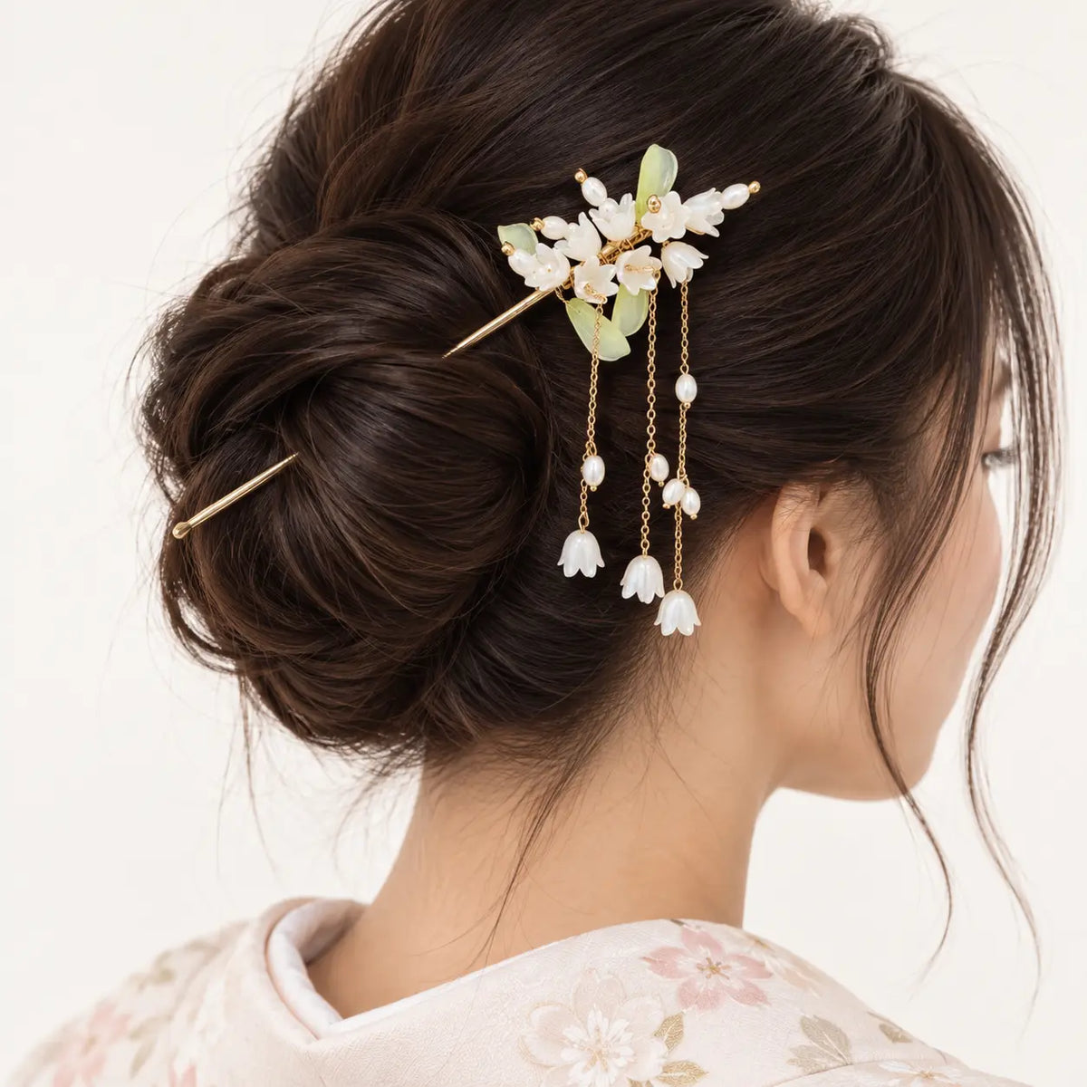 Chignon orné d’un bijou à fleurs blanches et perles pendantes.