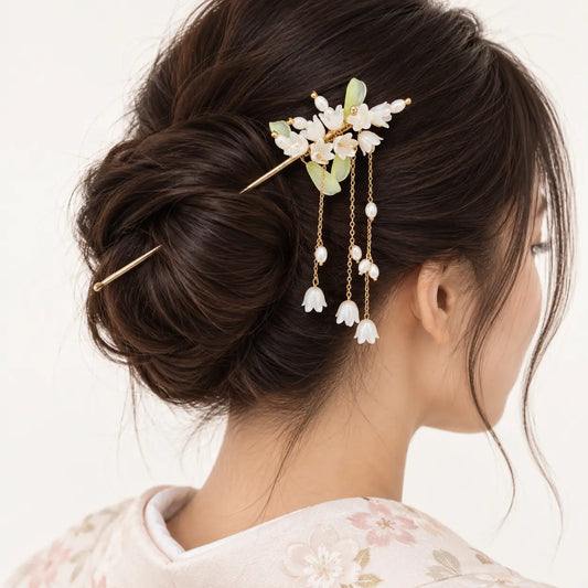 Chignon orné d’un bijou à fleurs blanches et perles pendantes.