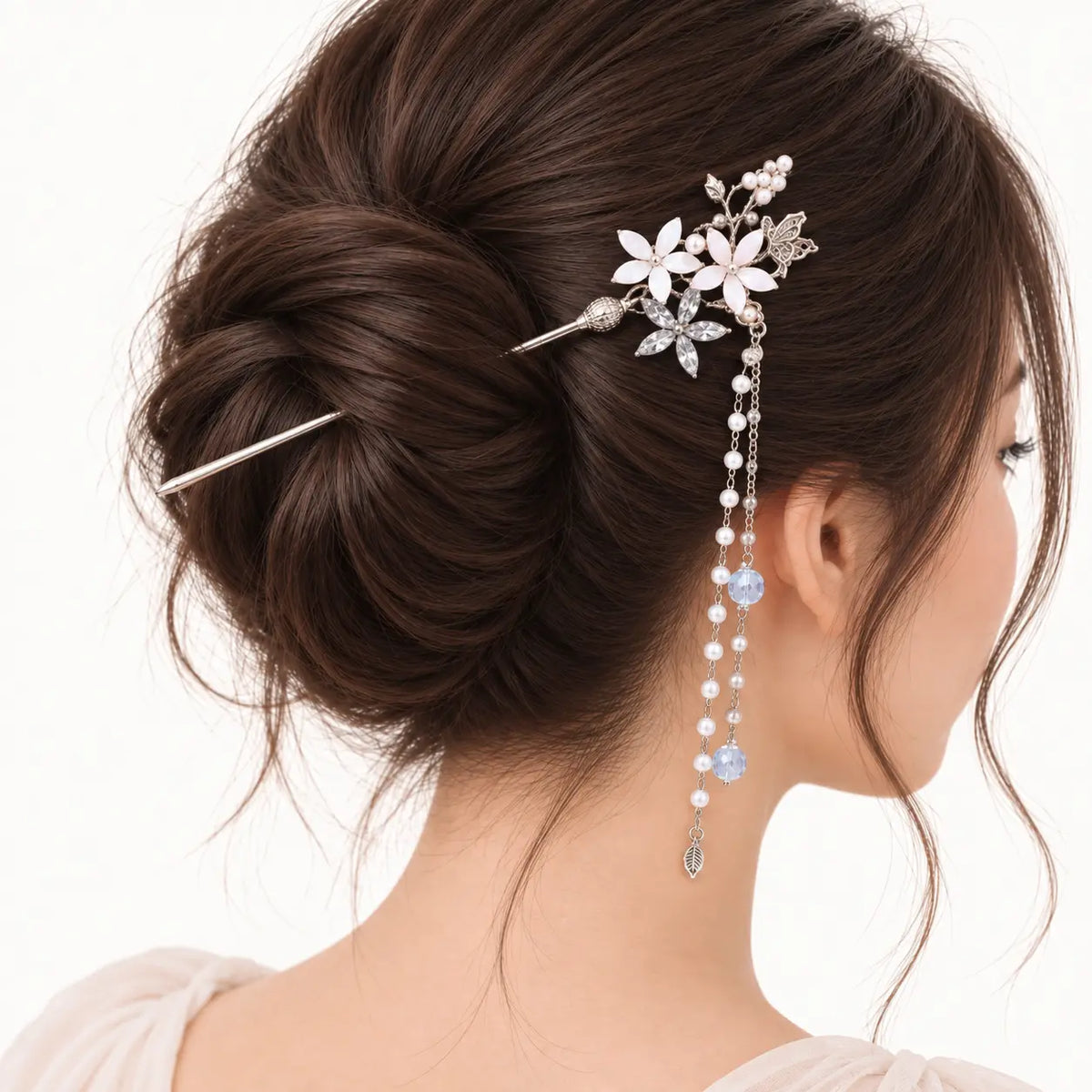 Chignon brun orné d’un bijou argenté à fleurs et longues perles bleutées.