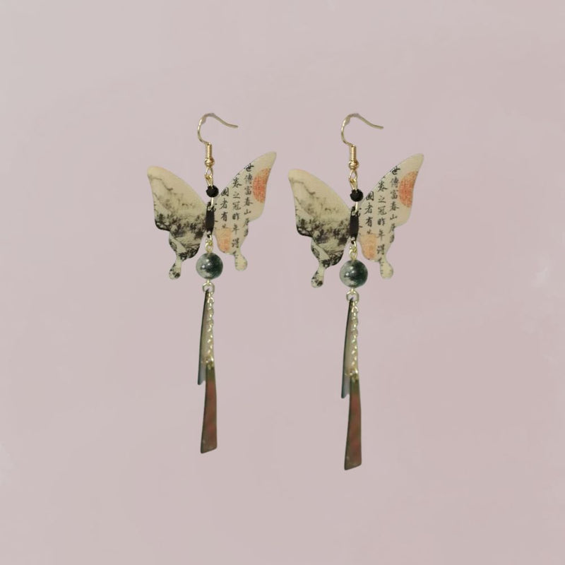 Boucles d'oreilles en forme de papillon, ornées de motifs asiatiques et de perles, suspendues à un fond pastel. Kimono femme.