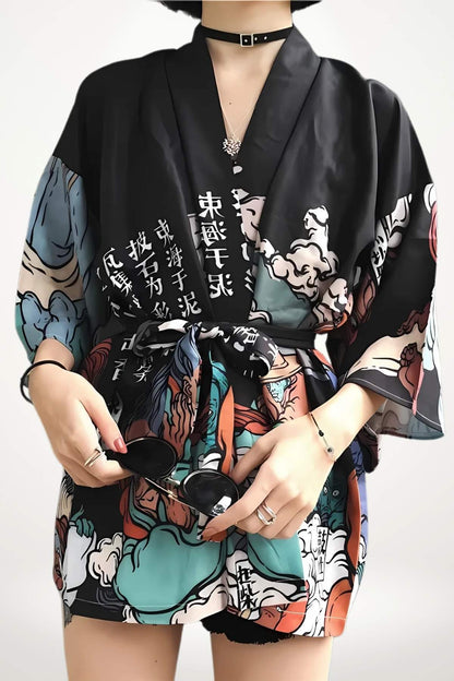 Cardigan kimono noir avec motifs colorés, ceinture nouée, porté par une femme tenant des lunettes de soleil