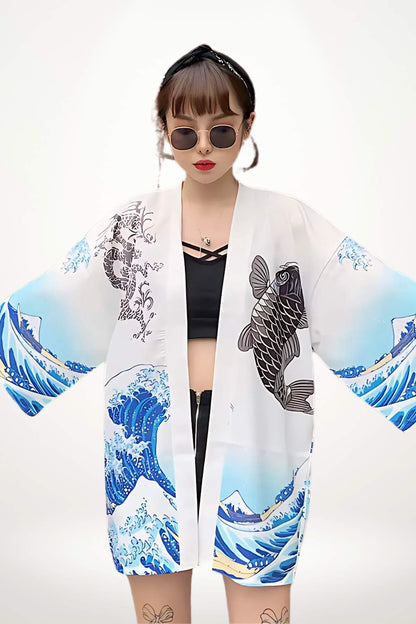 Femme portant un cardigan kimono blanc avec motifs de vagues et de poissons, lunettes de soleil et décor minimaliste