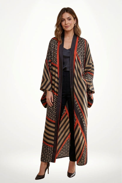 Femme portant un cardigan kimono aux motifs géométriques noirs, rouges et beiges, avec des manches larges et un fond clair