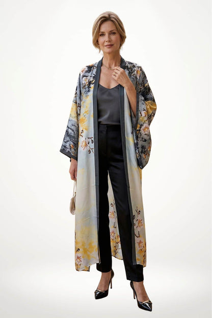 Femme portant un cardigan kimono aux motifs floraux, avec un pantalon noir et des escarpins brillants, sur fond blanc